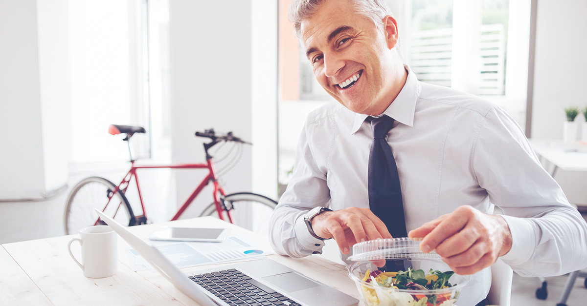 Business man eating healthy lunch with bike in background
