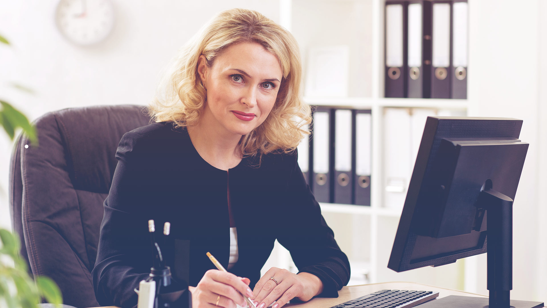Professional woman sitting at desk smiling at camera