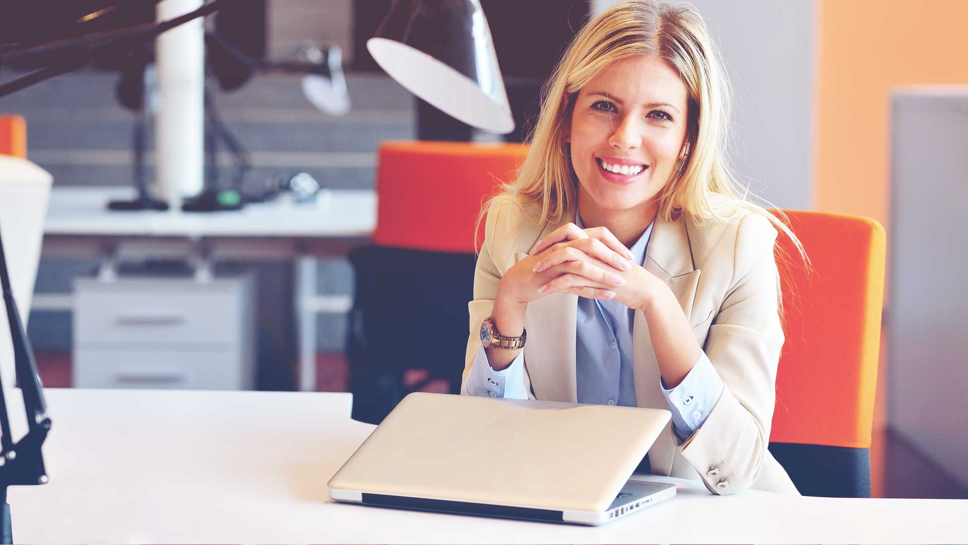 smiling professional woman at desk with closed laptop